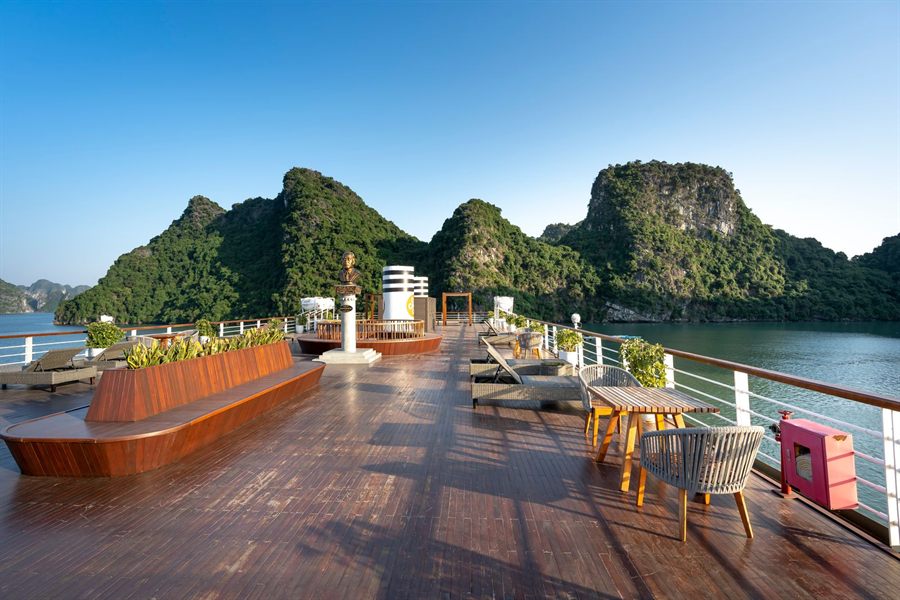 Wide ship sun deck with plants and seating looking out at green islands